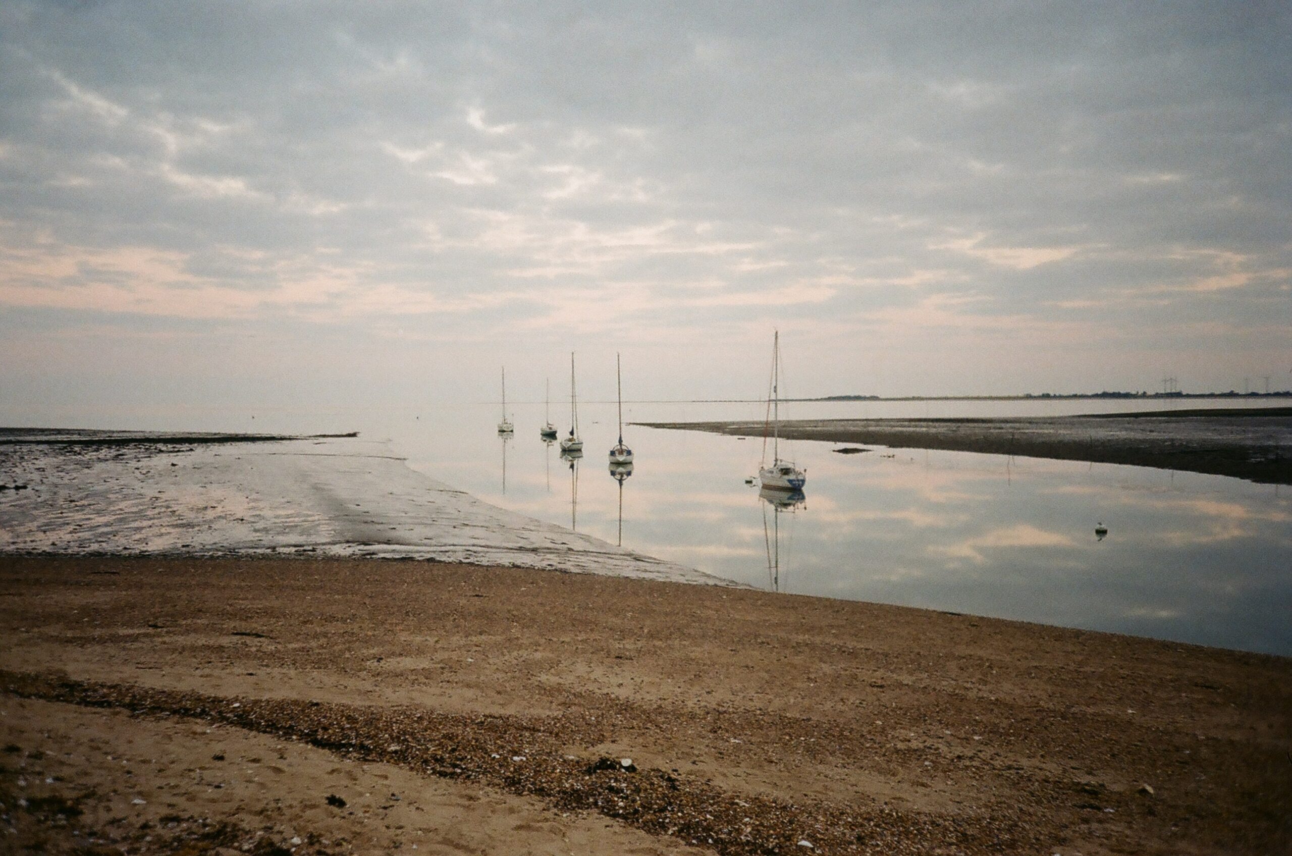 Mersea Island beach with boats in the distance on the sea water - outside catering colchester picnic spot